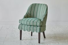 a green and white patterned chair sitting on top of a hard wood frame floor next to a wall