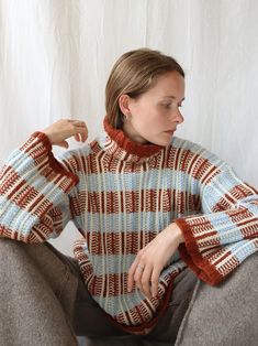 a woman sitting on the ground wearing a sweater