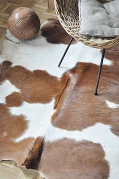 a brown and white cowhide rug on the floor next to a chair with a basketball