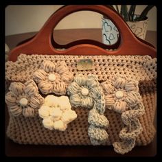 a crocheted purse with flowers on it sitting on top of a wooden table