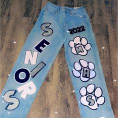 a pair of blue jeans with paw prints on the side and numbers painted on them