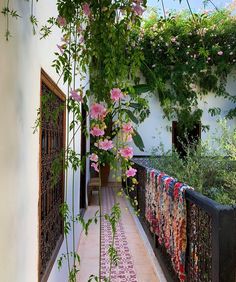 an outdoor area with pink flowers and greenery on the walls, along with a tiled floor