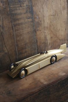 a toy batmobile sitting on top of a wooden table next to a wood wall