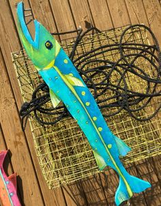 two colorful fish sculptures sitting on top of a wooden table next to wires and wire