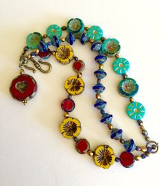 "Colorful bohemian style Czech glass multi strand flower bracelet with vintage bronze clasp and large Czech glass red heart bead charm. Bracelet is made of three separate but attached beaded strands of gorgeous Czech glass beads including: Sunflower yellow Picasso chunky pansy Cobalt blue Picasso UFO beads Turquoise/teal opaque gilded gold daisy coin beads Turquoise Hawaiian flower coral/teal/ turquoise beads Red Czech lentil beads Metallic bronze Czech fire polished faceted beads Gunmetal Czech Bohemian Red Bracelets Made Of Czech Glass, Bohemian Jewelry With Heart Beads In Flower Shape, Bohemian Red Czech Glass Bracelets, Bohemian Red Heart-shaped Bracelet, Bohemian Czech Glass Jewelry With Heart Beads, Red Flower-shaped Bohemian Beaded Bracelets, Red Bohemian Flower Beaded Bracelets, Bohemian Red Flower Bracelets, Bohemian Red Flower Beaded Bracelet