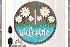 a welcome sign with daisies and an umbrella in the center is hanging on a door