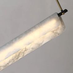 a white marbled light fixture hanging from a metal rod with a gold colored handle