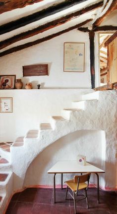 a room with stairs, table and pictures on the wall