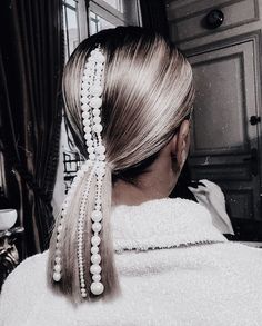 the back of a woman's head with long blonde hair and pearls in it