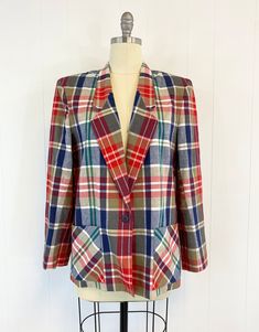 "80s plaid blazer with pockets featuring; ~ a notched lapel shoulder pads long sleeves single, navy blue button closure at the waist patch pockets at the hip hem hits low on hip boxy cut ~ of a smooth, mid weight, cotton in a large scale plaid in red, navy blue, kelly green, khaki and white ~ labeled \" Country Suburbans\", is made in the USA and is tagged a size 16, measurements when laid out flat are: 23 inches from pit to pit 24 1/2 inch sleeve 21 inches across bottom opening 28 1/2 inches fr Plaid Blazer With Patch Pockets For Fall, Fall Plaid Blazer With Patch Pockets, Retro Workwear Blazer With Welt Pockets, Retro Blazer With Welt Pockets For Work, Plaid Blazer With Pockets For Work, Vintage Plaid Blazer With Pockets, Vintage Workwear Blazer With Patch Pockets, Vintage Plaid Outerwear For Office, Vintage Blazer With Patch Pockets For Work