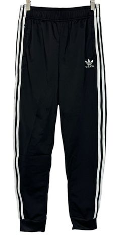 Add style and comfort to your athletic wardrobe with these black and white Adidas Superstar SST Track Jogger Pants in size L. Featuring an elastic waist with adjustable drawstring closure, these pants are perfect for travel, casual wear, and various sports activities such as soccer, hiking, and yoga. Made from polyester blended fabric, these pants offer easy care and are machine washable. The solid black color with Adidas stripes pattern adds a touch of sophistication to your outfit, while the tapered leg style and 26-inch inseam provide a great fit. These pants are perfect for boys who love comfort and style. White Adidas Superstar, Black And White Adidas, Adidas Pants, Sports Activities, White Adidas, Boys Who, Jogger Pants, Track Pants, Stripes Pattern