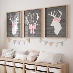 three framed deer head pictures hang on the wall above a bench with storage bins