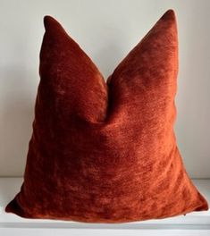 an orange pillow sitting on top of a white shelf