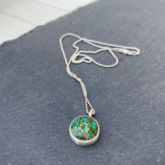 "Coming Down, Coming Down" Excellent multi-shades of green, a pretty spiderweb Hubei Turquoise round cabochon is set in fine and sterling silver, tumbled for a bright finish. Pendant measures approximately 20mm (including bail) by 15.5mm. 18" sterling silver bead chain with a sterling lobster clasp. Green Turquoise Pendant Necklace In Sterling Silver, Green Sterling Silver Turquoise Pendant Necklace, Round Chrysocolla Cabochon Jewelry, Artisan Chrysocolla Necklace, Green Cabochon Turquoise Pendant Necklace, Green Turquoise Necklace With Large Sterling Silver Pendant, Green Cabochon Round Necklaces, Handmade Green Turquoise Necklace In Sterling Silver, Unique Turquoise Necklace With Natural Stones