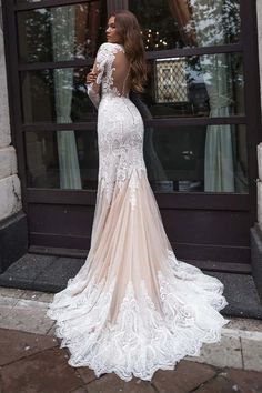 a woman standing in front of a building wearing a dress with long sleeves and open back