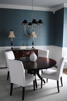 a dining room table with white chairs and a chandelier