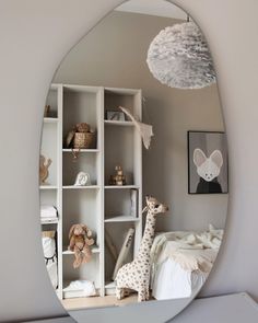 a mirror that has a giraffe on it in front of a book shelf