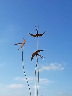 three tall metal birds on top of each other near the water and sand at the beach