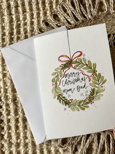 a christmas card with an ornament hanging from it's side on top of a blanket