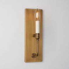 a wall mounted light with a candle on it's side next to a white wall