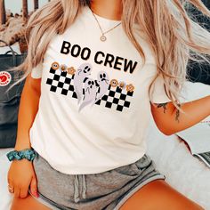 Boo Crew T-Shirt | Bella Canvas 3001 | Halloween Ghosts and Flowers Graphic Tee | Retro Spooky Shirt | Unisex Halloween T-Shirt | Cute Ghost T-Shirt ------------------------------------------------------------ Join the spookiest crew in town with our "Boo Crew" t-shirt! This playful Halloween tee features three adorable ghosts floating above a black and white checkered pattern, with a charming row of colorful flowers adding a cute twist to the design.  Perfect for those who love a mix of spooky Spooky Short Sleeve Shirt With Letter Print, Casual Halloween T-shirt With Letter Print, Casual Halloween Letter Print T-shirt, White Novelty Tops With Funny Print, Spooky Crew Neck Shirt With Letter Print, White Novelty Tops With Character Print, Cute Halloween T-shirt For Streetwear, Novelty White Short Sleeve Top, White Novelty Short Sleeve Top