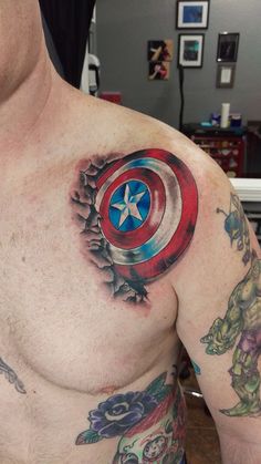 a man with tattoos on his chest is wearing a captain america shield and skull tattoo