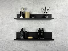 two black shelves with different types of items on them in front of a white wall