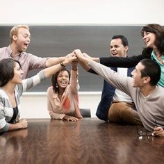 a group of people sitting around a table holding hands