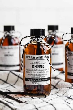 four bottles of homemade vanilla syrup on a tablecloth with black and white striped ribbon