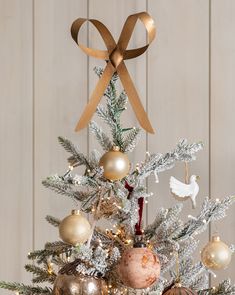 a small christmas tree with ornaments on it and a gold ribbon hanging from the top