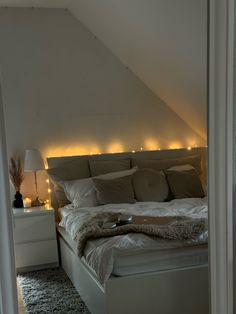 a white bed sitting in a bedroom next to a night stand with lights on it