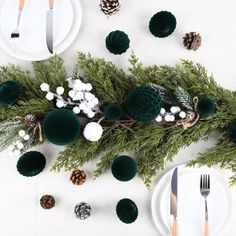 the table is set with pine cones and evergreen branches