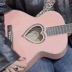 a close up of a person holding a pink guitar