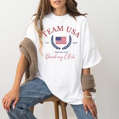 This USA Drinking Team Shirt is perfect for your next summer party for Memorial Day or 4th of July. Watch the Summer Games cheering on America in your new drinking shirt.  Comfort Colors introduces its garment-dyed t-shirt; a tee made 100% with ring-spun cotton. The soft-washed, garment-dyed fabric brings extra coziness to your wardrobe while the relaxed fit makes it an excellent daily choice. The double-needle stitching throughout the tee makes it highly durable while the lack of side-seams hel White Team Spirit T-shirt For Summer, Summer Team Spirit T-shirt With Graphic Print, Summer Team Spirit Crew Neck T-shirt, Summer Team Spirit Top With Graphic Print, Summer Team Spirit Screen Print Top, Summer Tops With Graphic Print For Team Spirit, Summer Team Spirit T-shirt, Summer Cotton T-shirt With Team Spirit Style, Summer Cotton T-shirt With Team Spirit