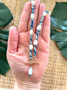 Welcome to our Coastal Inspired Beaded Pearl Necklace – a stunning blend of elegance and coastal charm, inspired by the breathtaking coastline of Santorini, Greece! 🌊✨Crafted with care and attention to detail, this necklace features a beautiful combination of unique tie-dyed bright blue and white coconut shell heishi beads, reminiscent of the colors of the Aegean Sea, and lustrous 9mm freshwater pearls. Each bead is carefully selected to evoke the serene beauty of Santorini's coastline, creatin Artisan Blue Jewelry For The Beach, Artisan Blue Jewelry For Beach, Elegant Handmade Blue Shell Necklace, Ocean-inspired Blue Strand Jewelry, Blue Ocean-inspired Jewelry For Vacation, Blue Ocean-inspired Strand Jewelry, Ocean-inspired Strand Necklaces For Jewelry Making, Ocean-inspired Blue Pendant Jewelry, Blue Strand Necklace With Ocean-inspired Style