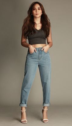 a woman in high waisted jeans poses for the camera