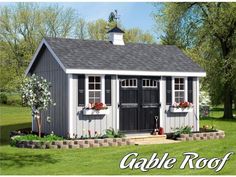 a small gray and white shed sitting on top of a lush green field