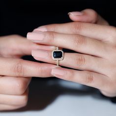 a woman's hand holding an engagement ring with a black stone in it and diamond accents on the band