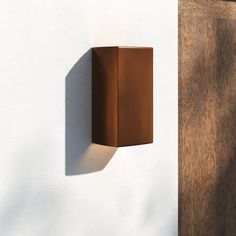 a wall light mounted on the side of a white building next to a wooden door