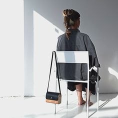 a woman sitting in a chair with her back to the camera and holding a purse