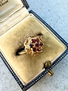 This is a vintage 9ct Gold Garnet Cluster Ring. 7 vibrant garnets create a lovely cluster and are set in a decorative yellow gold setting. Ring size N  Weight: 2.69 grams approximately. The ring is marked with full London hallmarks, 9. 375 for 9ct Gold and dates to 1967. Please note all sizes and measurements are approximate. Comes with box. Box may differ from that in photos. As most of our pieces are vintage finds they only come in one size. However if you require your ring to be sized so it's Vintage Garnet Birthstone Rings, Vintage Gold Cluster Ring With Gemstones, Vintage Cluster Ring Suitable For Gifts, Vintage Cluster Rings For Gifts, Vintage Cluster Rings As Gift, Vintage Garnet Birthstone Ring For Wedding, Vintage Garnet Cluster Ring With Gemstone, Vintage Garnet Birthstone Ring In Yellow Gold, Vintage Gold Garnet Birthstone Ring