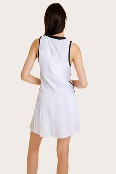 the back view of a woman wearing a white dress with pleated skirt and black top