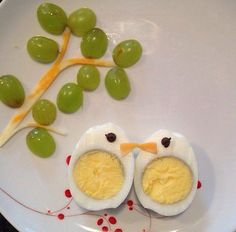 an egg with two halves cut in half on a plate next to grapes and a sticker that says enjoy joy