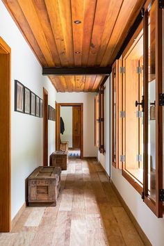 an empty hallway with wood paneling on the ceiling and wooden benches in front of it