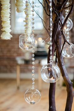 some clear bubbles hanging from a tree in a room with wood flooring and brick walls