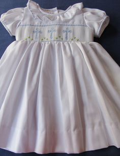 White dress hand smocked with delicate light blue crosses. Ties on the back Easter dress or christening dress is a beautiful dress delicately smocked with crosses. This dress can also be used not just for that special occasion or for any other special event, dedication or for older girls their First Holy Communion and portraits. Made to order. For customs made orders allow 2-3 weeks for delivery. Elegant Smocked Dress With Smocked Cuffs For Baptism, Elegant Smocked Ruffle Dress For Baptism, Elegant Blue Dress For Confirmation, Spring Baptism Dress With Smock Detail, White Baptism Dress With Smocked Bodice For First Communion, White Fitted Smocked Dress For Baptism, Elegant Baptism Dress With Smocked Bodice, Fitted Smocked Dress For Baptism In Summer, Elegant White Smocked Dress For Baptism