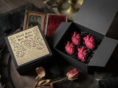 a box filled with red hearts sitting on top of a table next to a rose