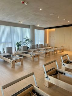 an empty room with wooden tables and benches in it's center, next to a large window