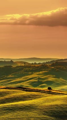 the sun is setting over rolling hills and trees