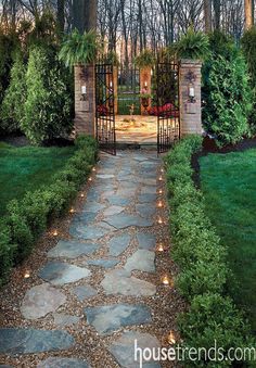 a stone path leads to an open gate in the middle of a lush green yard